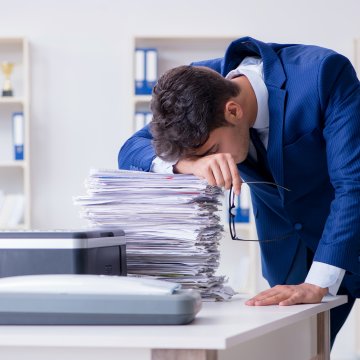 man young office tired blue suit head on files fax machine online faxing nextiva vfax